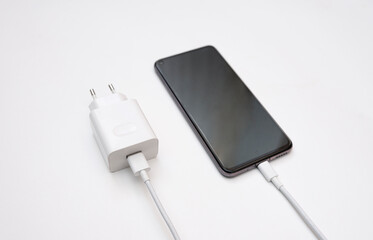 Charging a smartphone via a USB cable on a white background, top and side view. Silhouette of black...