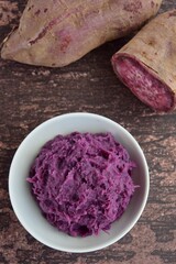 Mashed purple sweet potato in a bowl on wooden background. flat lay, 