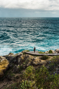 Woman looking over choppy water in Robberg Nature Reserve, South Africa. September 2019