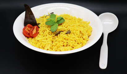 Cooked turmeric jasmine rice with powdered curcumin or Haldi, Indian food, indian basmati rice homemade with tomato and Cardamom.
