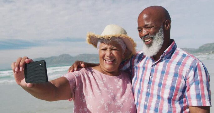 Mixed race senior couple taking a selfie with a smartphone at the beach