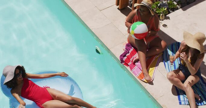 Diverse group of female friends having fun at pool bouncing ball