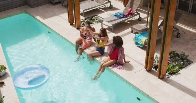 Diverse group of female friends having fun drinking wine at pool