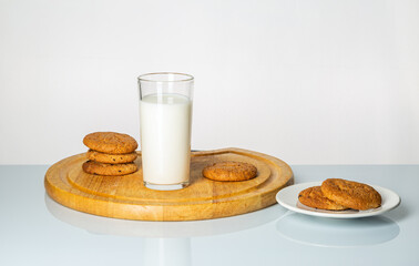 A glass of milk and cookies on a table on a white background.