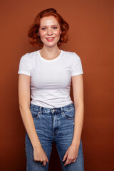 Obraz premium young pretty redhead girl posing cheerful on warm brown background, lifestyle people concept