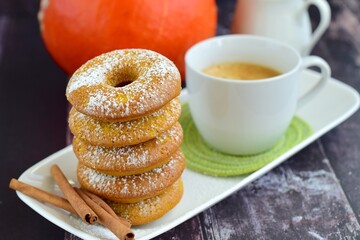 Stacks of pumpkin donuts with a cup of coffee