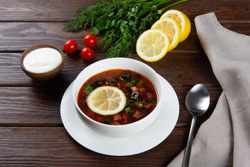 Meat hodgepodge with lemon on brown wooden table.