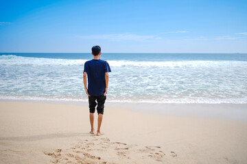 Fototapeta na wymiar a man in a blue shirt, looking at the sandy beach in need, beautiful and clean