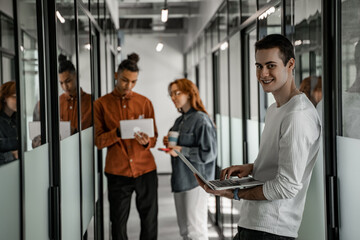 student using laptop near interracial classmates on blurred background