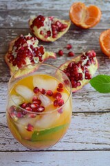 Tangerine juice with pomegranate and mint leaves in a glass full of ice cubes