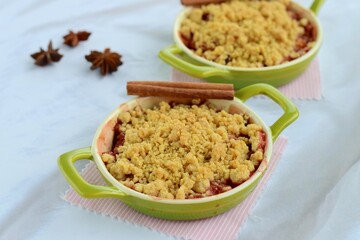 Plum crumble with spices on white background. Summer crispy fruit dessert. Tasty breakfast
