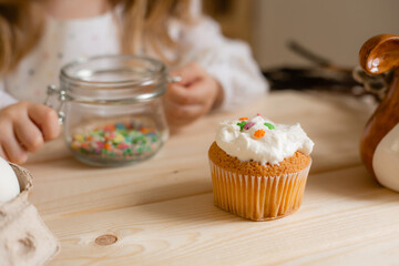 Cute little girl in a cotton dress at home in a wooden kitchen prepares an Easter cake