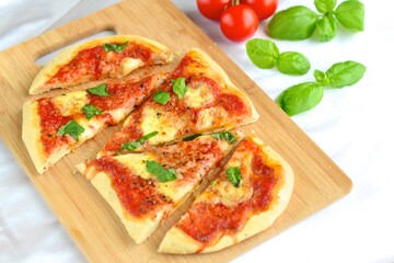 pizza with tomato sauce, mozzarella and basil leaves on wooden board