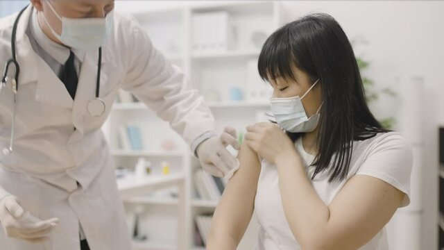 Doctor injecting vaccine to asian woman, immunization against disease, medicine