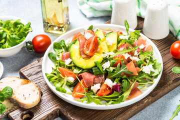 Fresh salad with green leaves, jamon and tomatoes.
