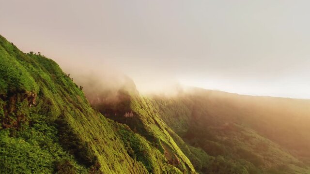 Drone flying along mountains in clouds of Poco Ribeira do Ferreiro, Alagoinha, Flores Island, Azores, Portugal, Europe. Aerial view of cliffs covered green vegetation, 4k footage