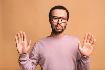 Portrait of African American male holding hand in stop sign, warning and preventing you from something bad, looking at the camera with worried expression. Selective focus on the palm