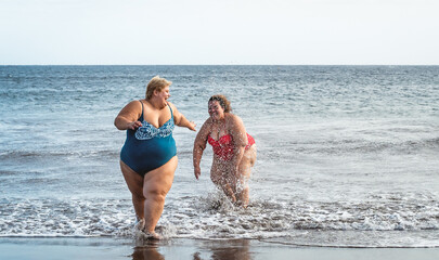 Happy plus size women having fun on the beach during summer vacation - Curvy confident people lifestyle concept