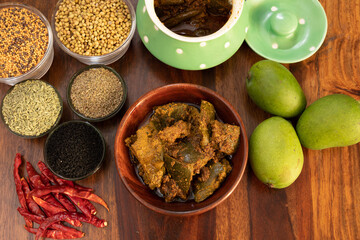 Mango pickle or Aam ka Achar top view with indian spices and chillies and raw mango isolated on wooden background