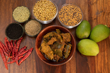 Indian mango pickle or aam ka aachar top view with traditional spices on a wooden background selective focus
