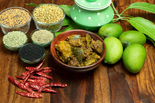 Homemade Mango Pickle or Mango Pickel or aam ka achar or Kairi Loncha in a wodded bowl with Spices and jar and Raw Mango, selective focus