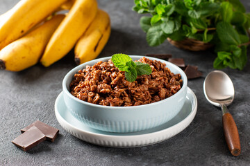 Chocolate oatmeal with banana - healthy vegetarian breakfast on a wooden table