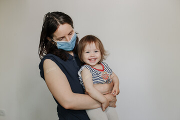 mother and daughter, a child after vaccination. A woman in a medical mask. Happy joyful child