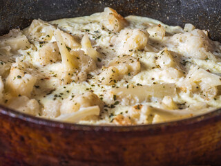 Cauliflower with eggs and milk in a pan close-up