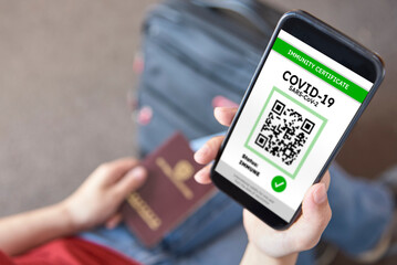 Young woman about to travel holding a smartphone with a certificate of immunity