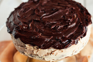 Delicious round cake with white buttercream topped with chocolate frosting, coating