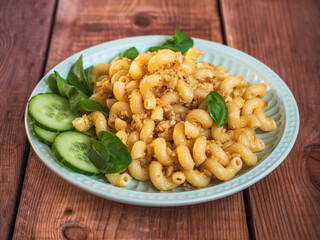 Breakfast with minced chicken pasta and basil leaves on a ceramic salad plate