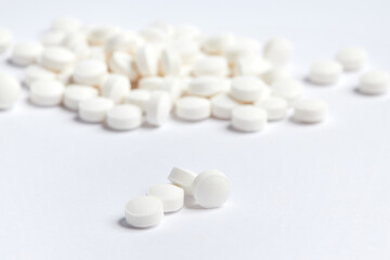 White round pills on a white background. A heap of small round meds. Health care and medicine concept