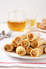 Crepes, thin pancakes with honey and tea on a white plate.