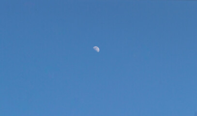 View of the half moon in the afternoon in the blue sky