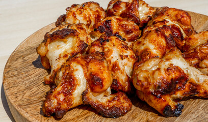 Delicious Roasted Chicken drumsticks on wooden plate, close-up