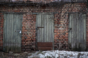 Brick shed with shabby wooden doors. Three wooden doors