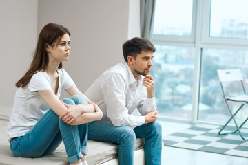 man and woman sitting on the bed at home near the window communication