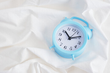 Fototapeta na wymiar blue alarm clock and cotton flower on bed