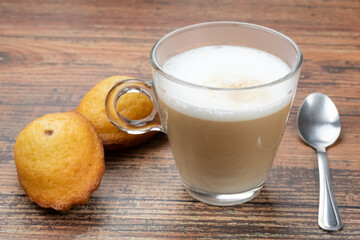 tasse de café au lait et madeleine sur une table