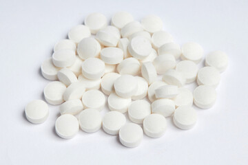 White round pills on a white background. A heap of small round meds. Health care and medicine concept