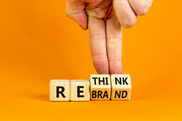 Rethink and rebrand symbol. Businessman turns cubes and changes the word 'rethink' to 'rebrand'. Beautiful orange background. Business, rethink and rebrand concept. Copy space.