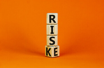 Risk vs rise symbol. Turned a wooden cube and changed the word risk to rise. Beautiful orange background, copy space. Business, risk vs rise concept.