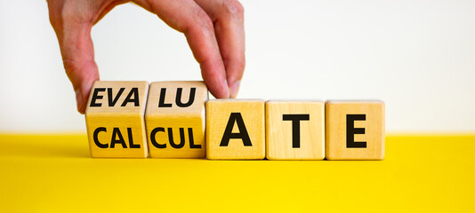 Calculate or evaluate symbol. Businessman turns wooden cubes and changes the word 'evaluate' to 'calculate'. Beautiful yellow and white background, copy space. Business, calculate or evaluate concept.