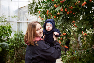 Mother and baby enjoying time together in orangery. Background with Nature plant and leaf environment. Mothers day