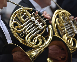 A French horn in the hands of a musician, during a classical music concert