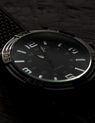 
details of elegant silver watch with black wood background