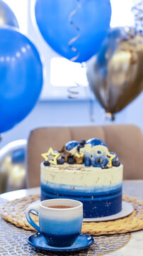 Handmade birthday cake on a blurred background with balloons and sparkles. Cheesecake cake, blue and gold accents. Festive background for postcard, holiday, birthday, anniversary, 18 years. 