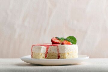 Delicious cheesecake with fresh strawberries and mint on white plate.