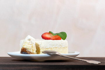 Classical New York cheesecake with slice cut out and dessert spoon.