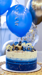 Handmade birthday cake on a blurred background with balloons and sparkles. Cheesecake cake, blue and gold accents. Festive background for postcard, holiday, birthday, anniversary, 18 years. 